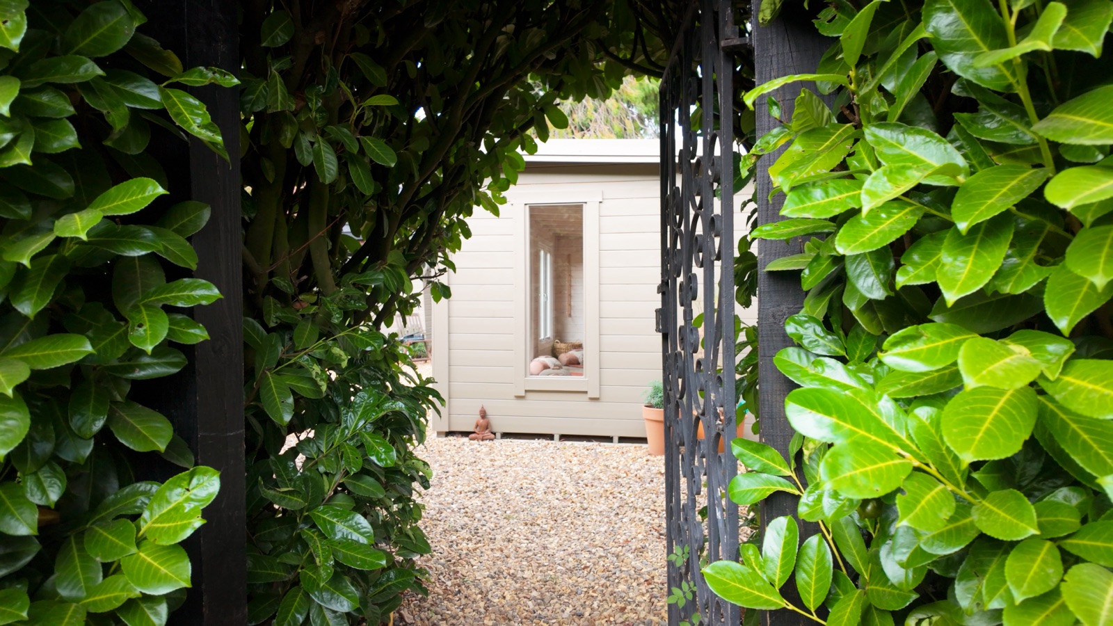 The garden studio seen through an archway of hedges